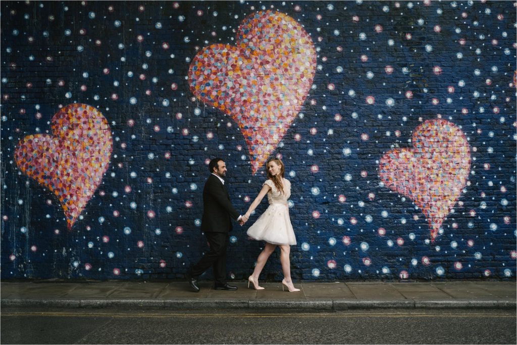 Bride and Groom walking together with romantic graffiti 