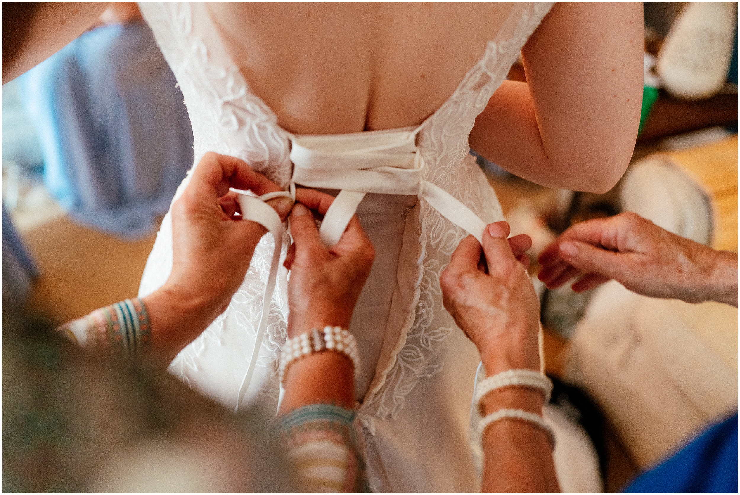 People helping lace up a wedding dress. 