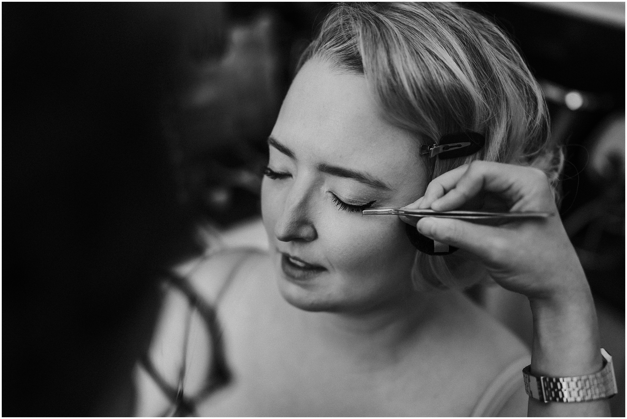 A black and white photo of a bride having her makeup done by Kylie McMichael. 