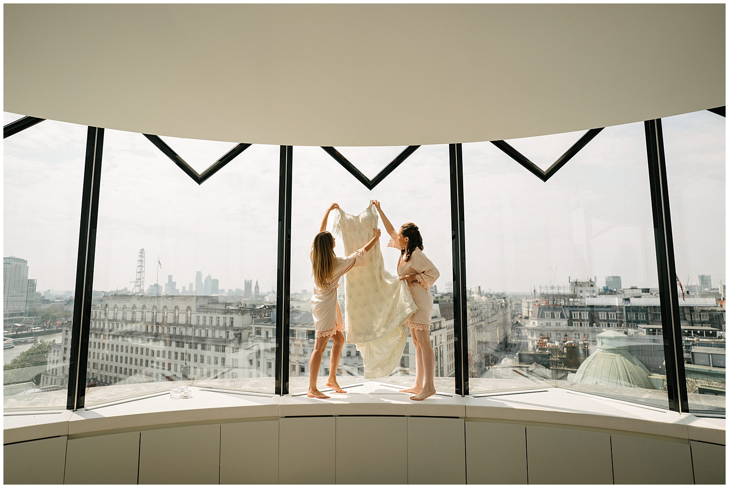 Bridesmaids hanging up a dress in a window. 