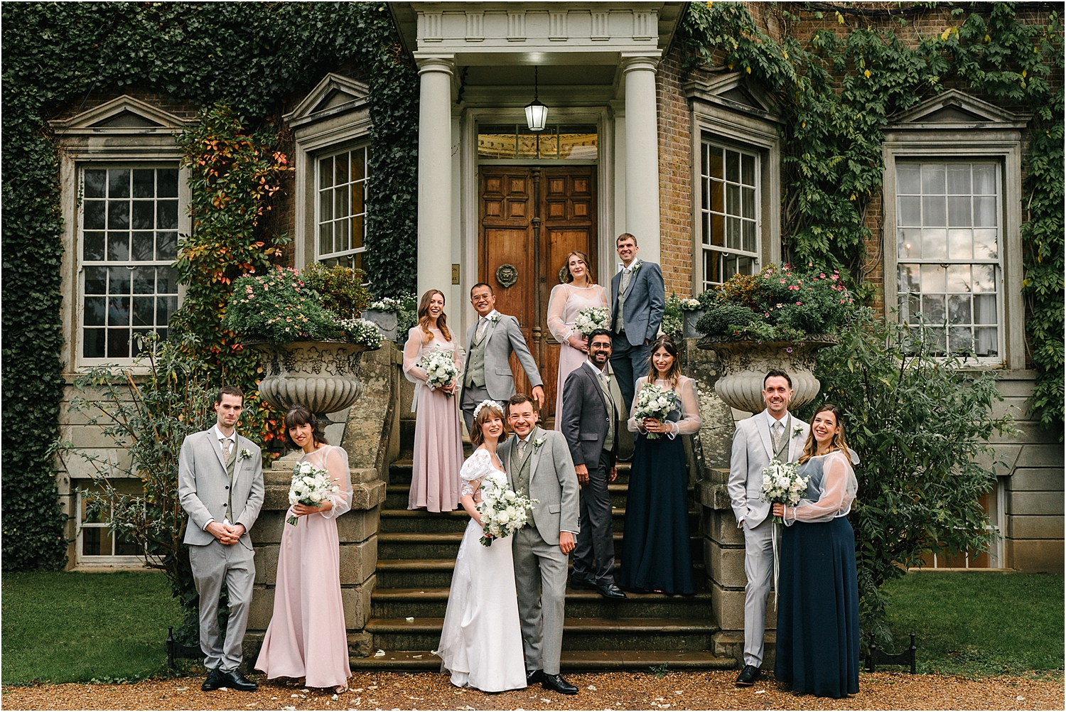 A wedding party group shot outside Hampton Court House. 