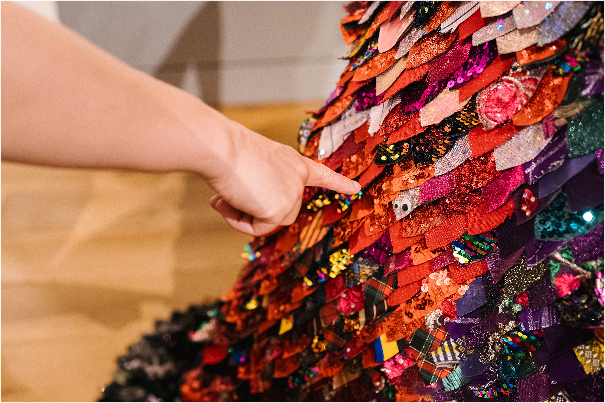 A wedding guest admiring the detail of a colourful wedding dress. 