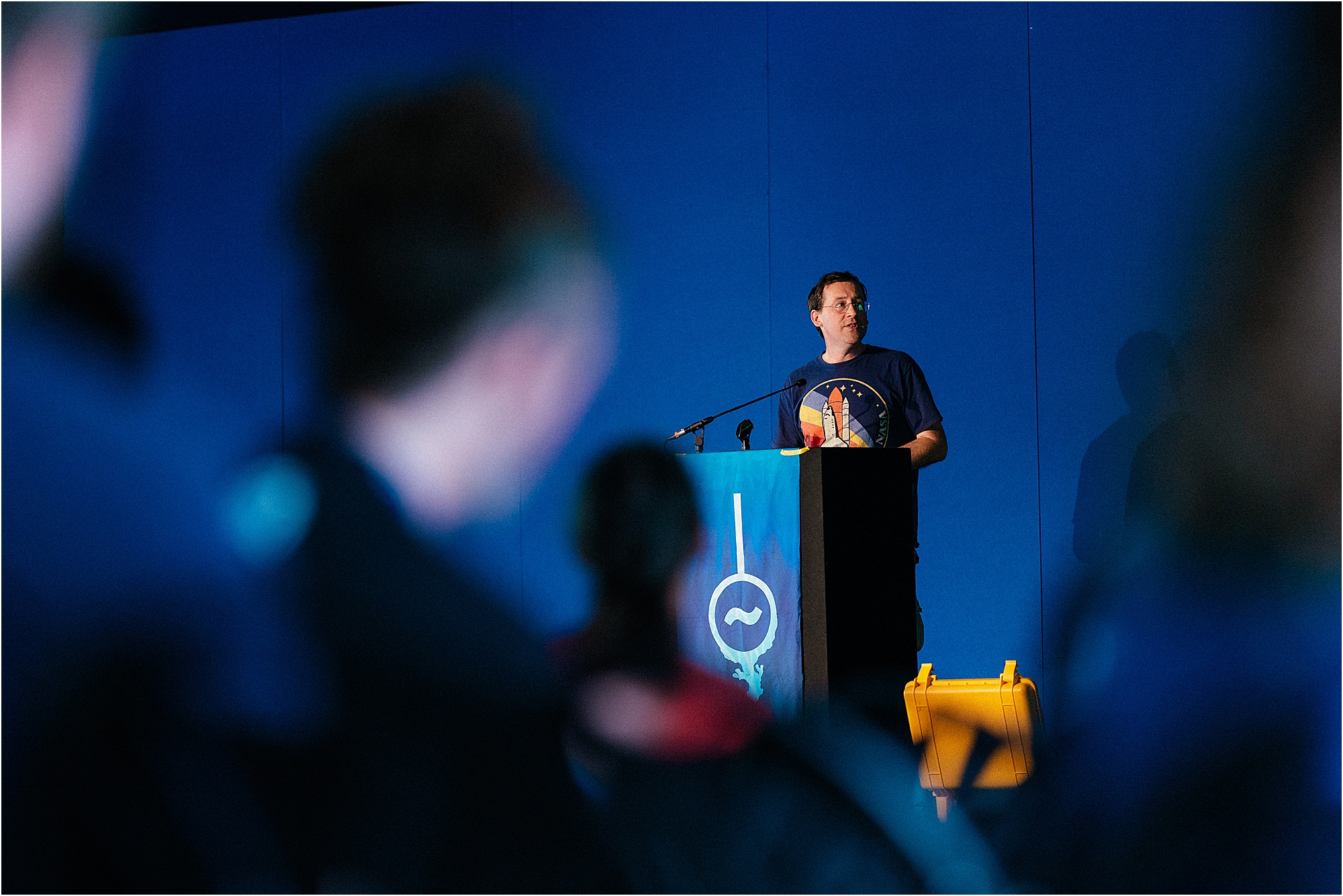 A photograph of a speaker giving a talk on a stage at a festival. Photograph by Kari Bellamy. 